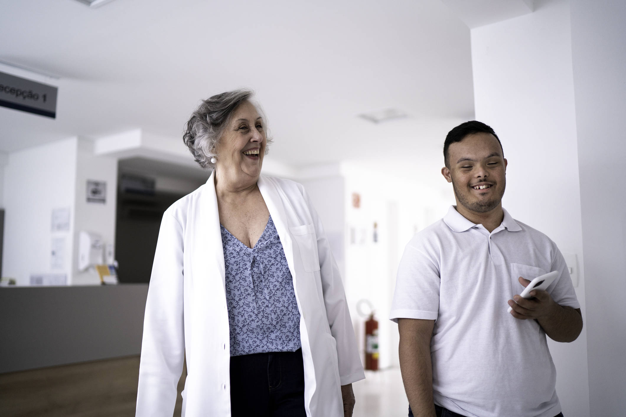 Female senior doctor welcoming / greeting special needs boy at hospital