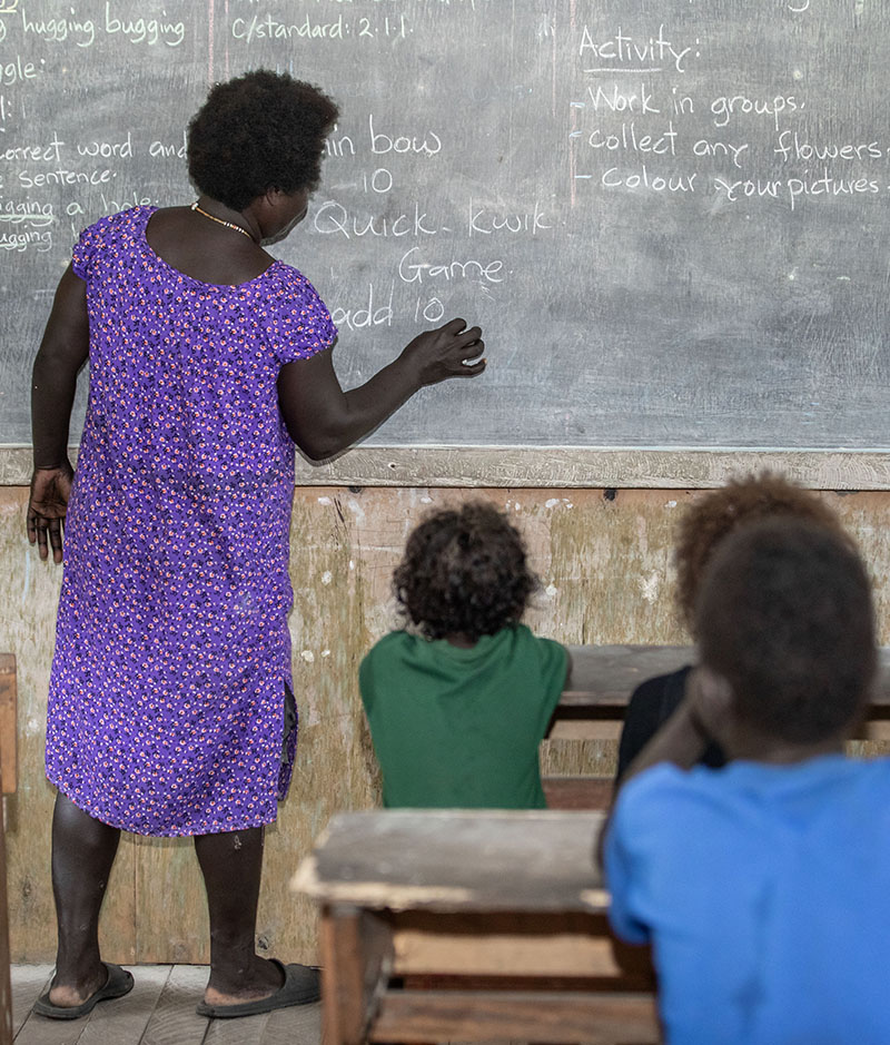teacher at a blackboard in front of a classroom of students