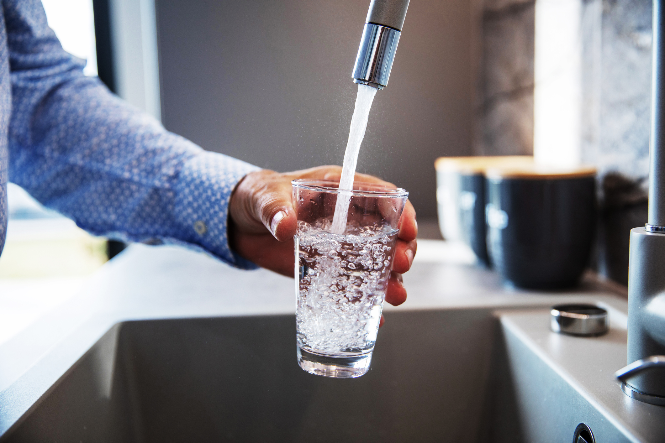 person filling glass with drinking water