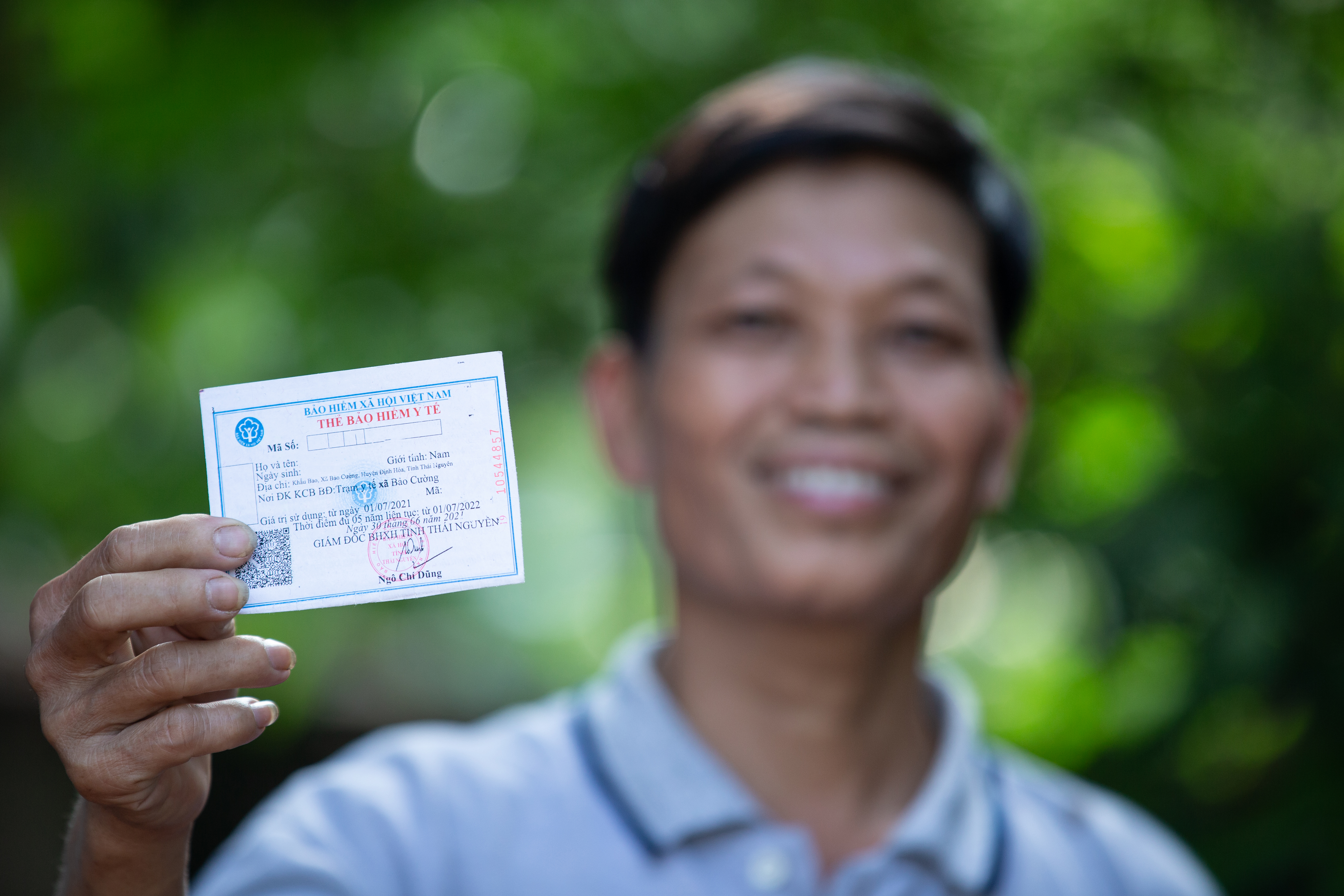Vietnamese man holding up his social health insurance card