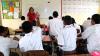 classroom in Fiji with a smiling teacher and students raising their hands
