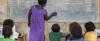 teacher at a blackboard in front of classroom of students